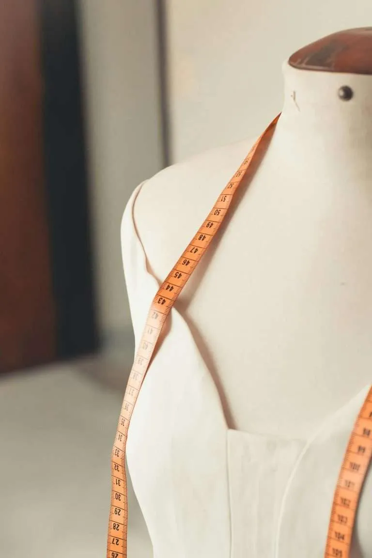Measuring tape draped on dress form mannequin