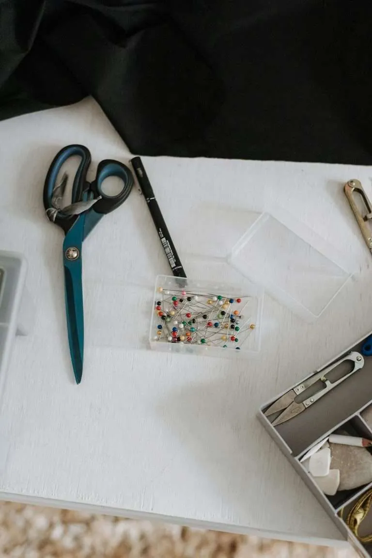 Sewing pins with scissors in studio workspace