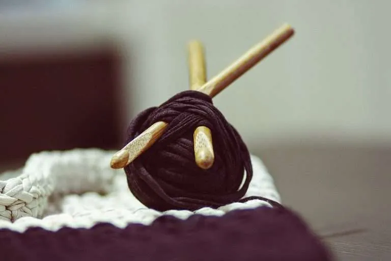 Balls of wool yarn beside a pair of wooden knitting needles
