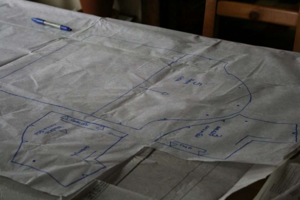 Sewing pattern pieces traced in blue pen onto tissue paper, with notches and grainlines marked